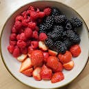 A variety of fresh raspberries, strawberries, and blackberries in a bowl, perfect for summer snacks.